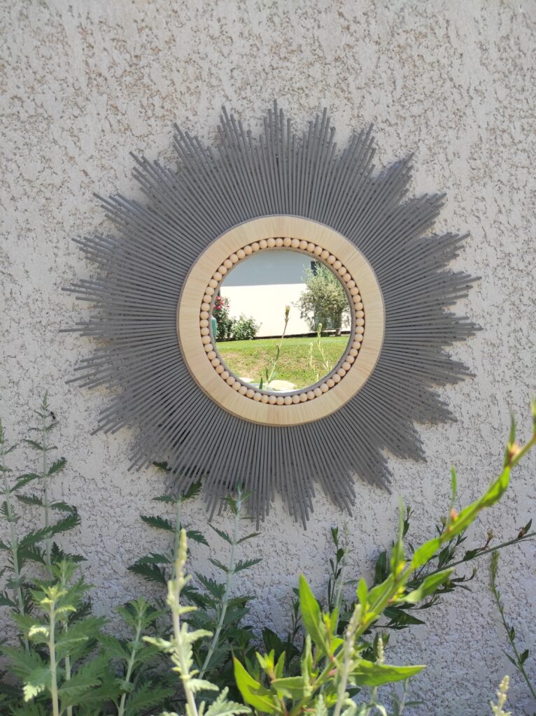 Création française, miroir rond en bois teinté d’un bleu gris tendance, d’un bord en raphia et de perles bois Ju0232