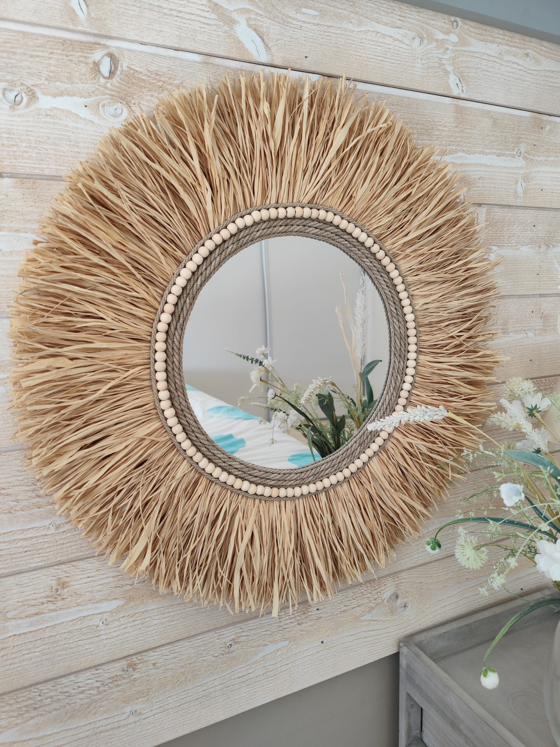 Miroir rond en raphia naturel, cerné de cordes de lin et de perles de bois.Réf Ju0276
