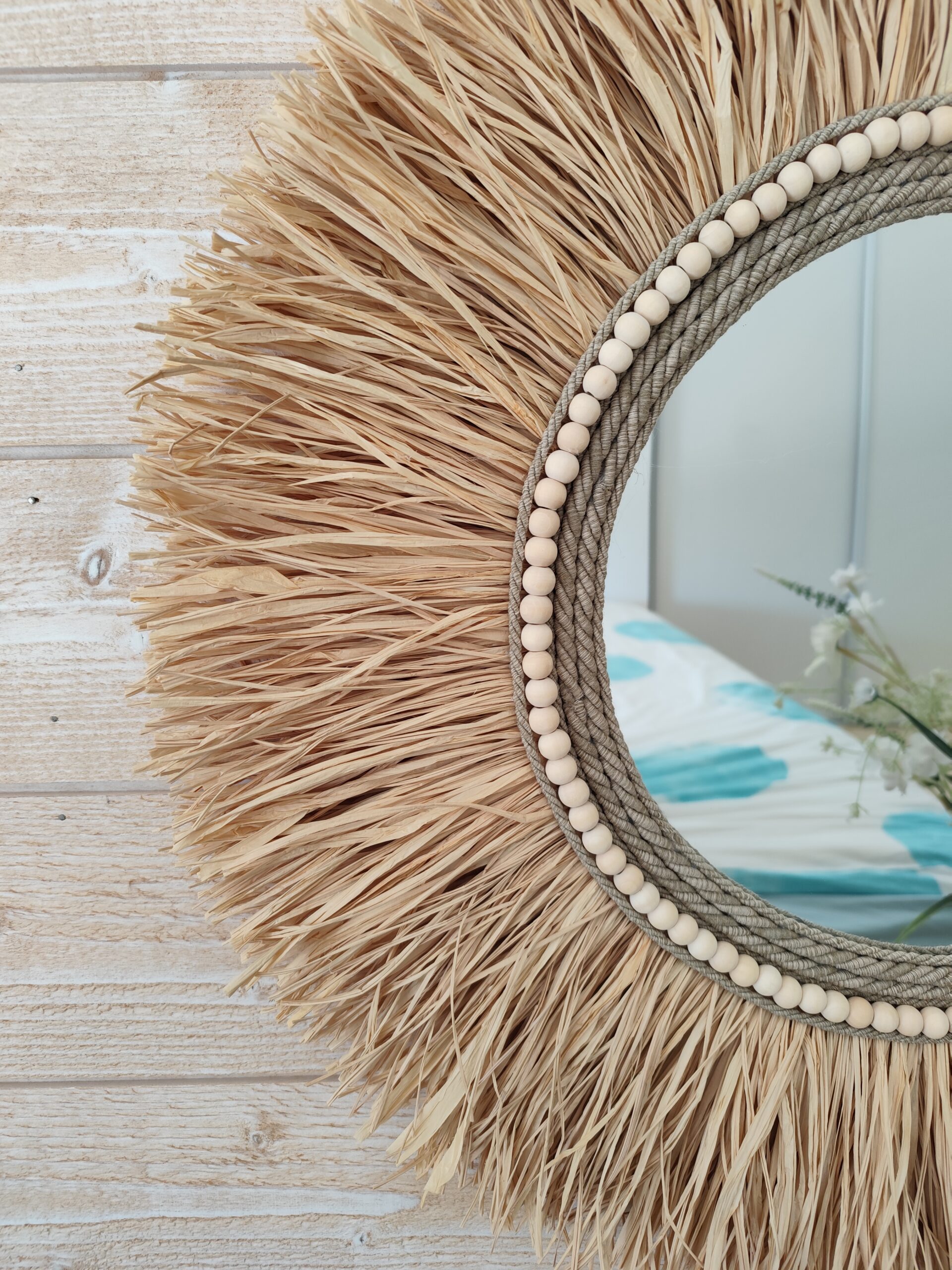 Miroir rond en raphia naturel, cerné de cordes de lin et de perles de bois.Réf Ju0276