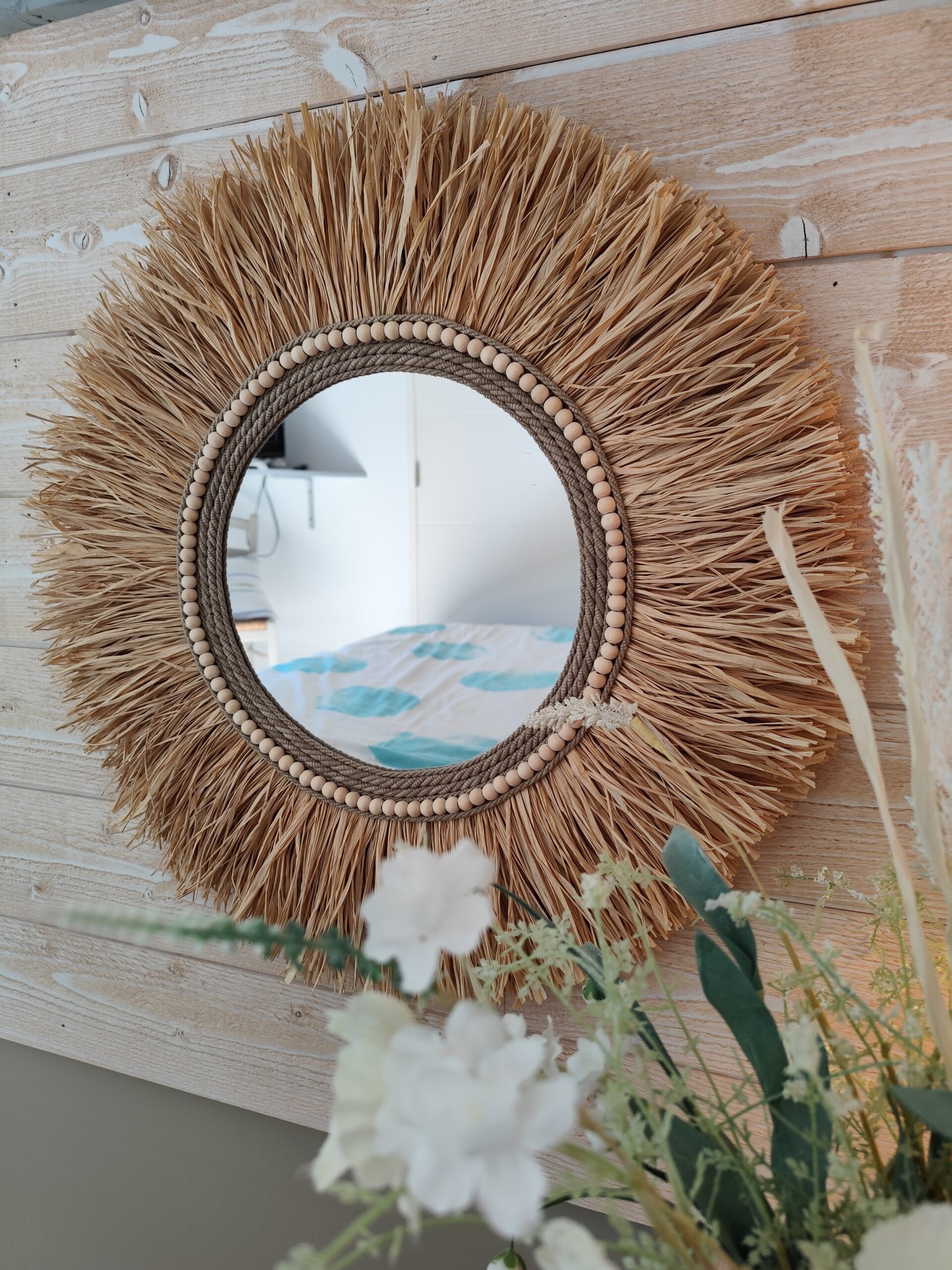 Miroir rond en raphia naturel, cerné de cordes de lin et de perles de bois.Réf Ju0276