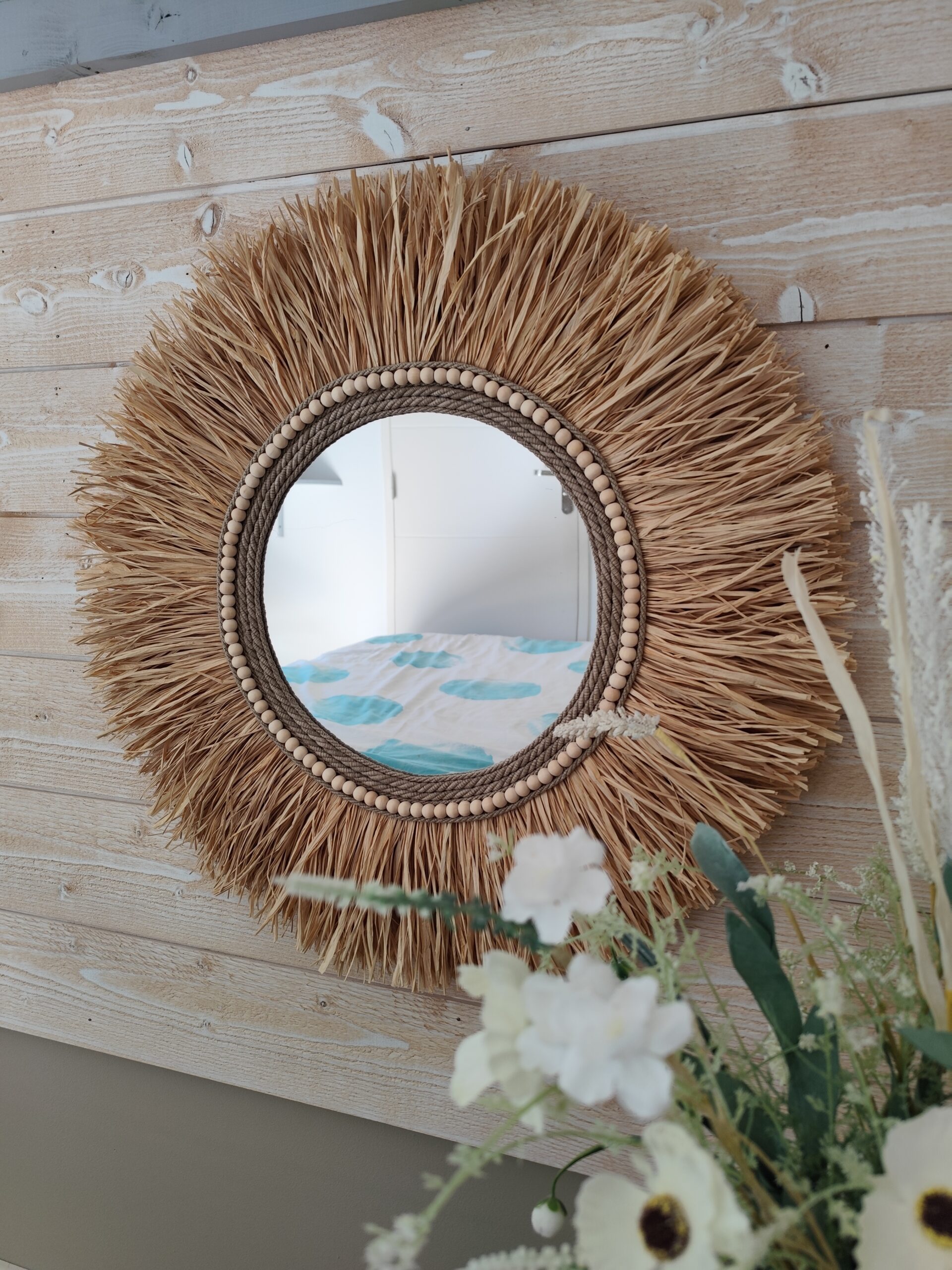Miroir rond en raphia naturel, cerné de cordes de lin et de perles de bois.Réf Ju0276