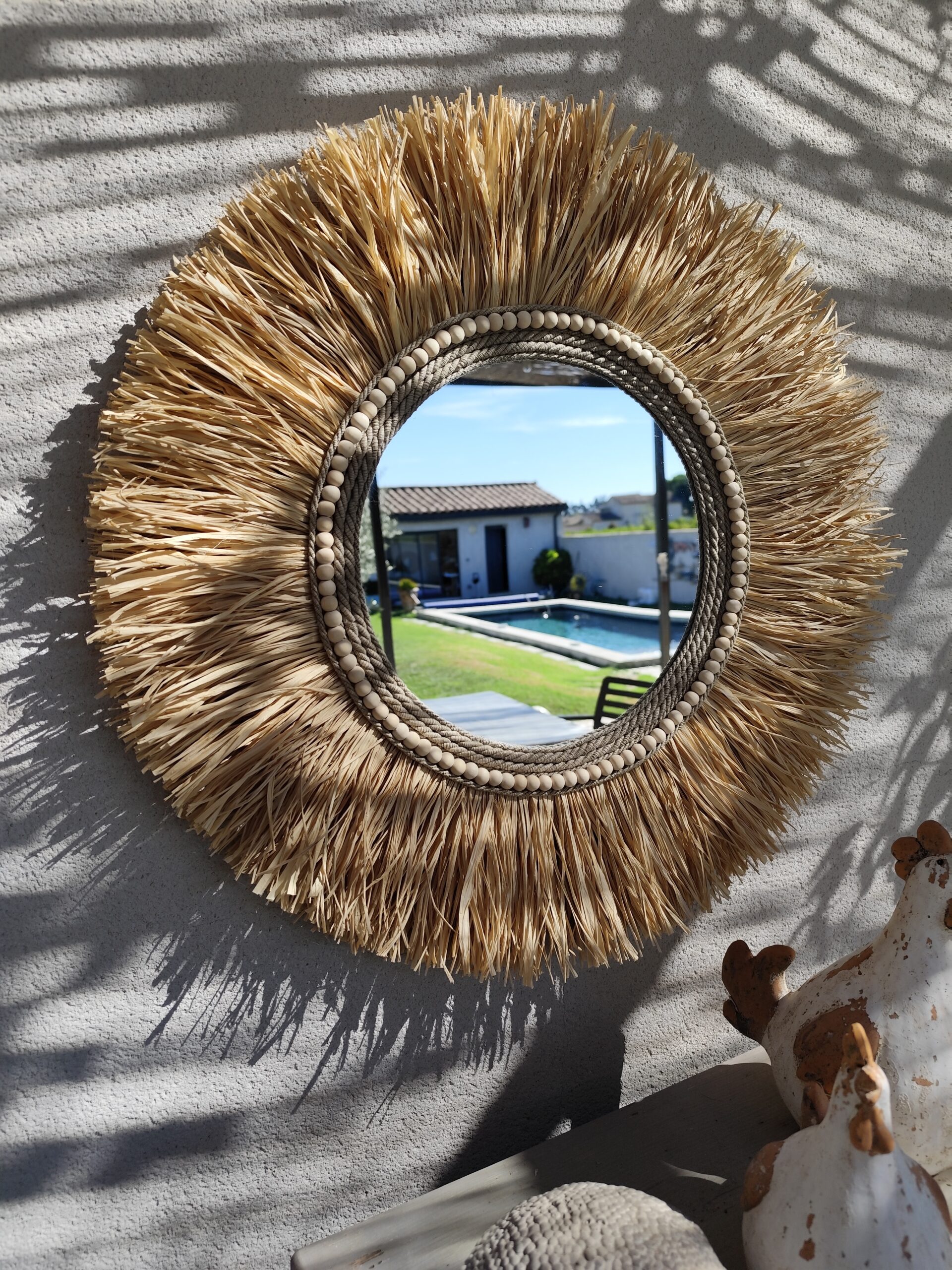Miroir rond en raphia naturel, cerné de cordes de lin et de perles de bois.Réf Ju0276