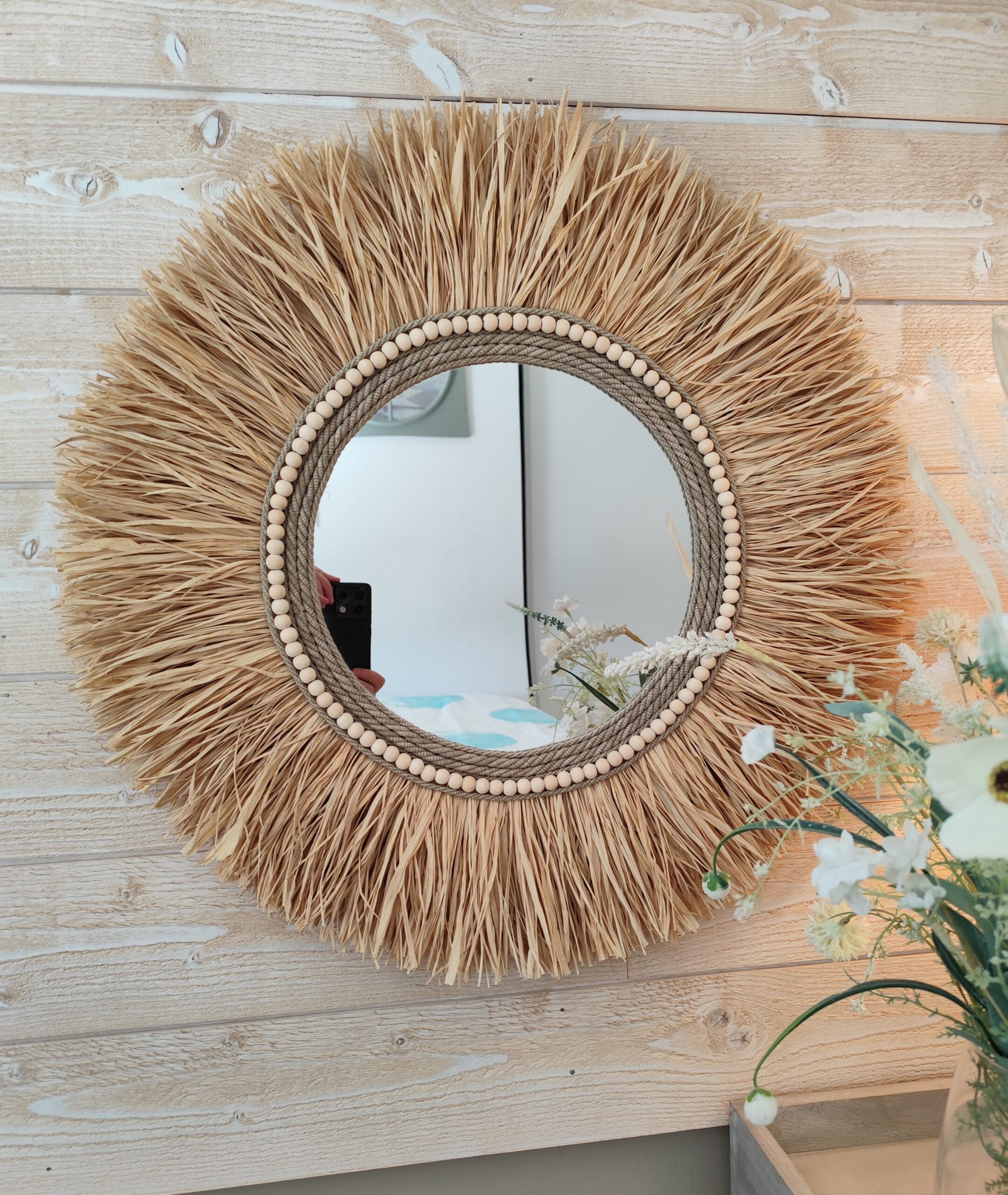 Miroir rond en raphia naturel, cerné de cordes de lin et de perles de bois.Réf Ju0276