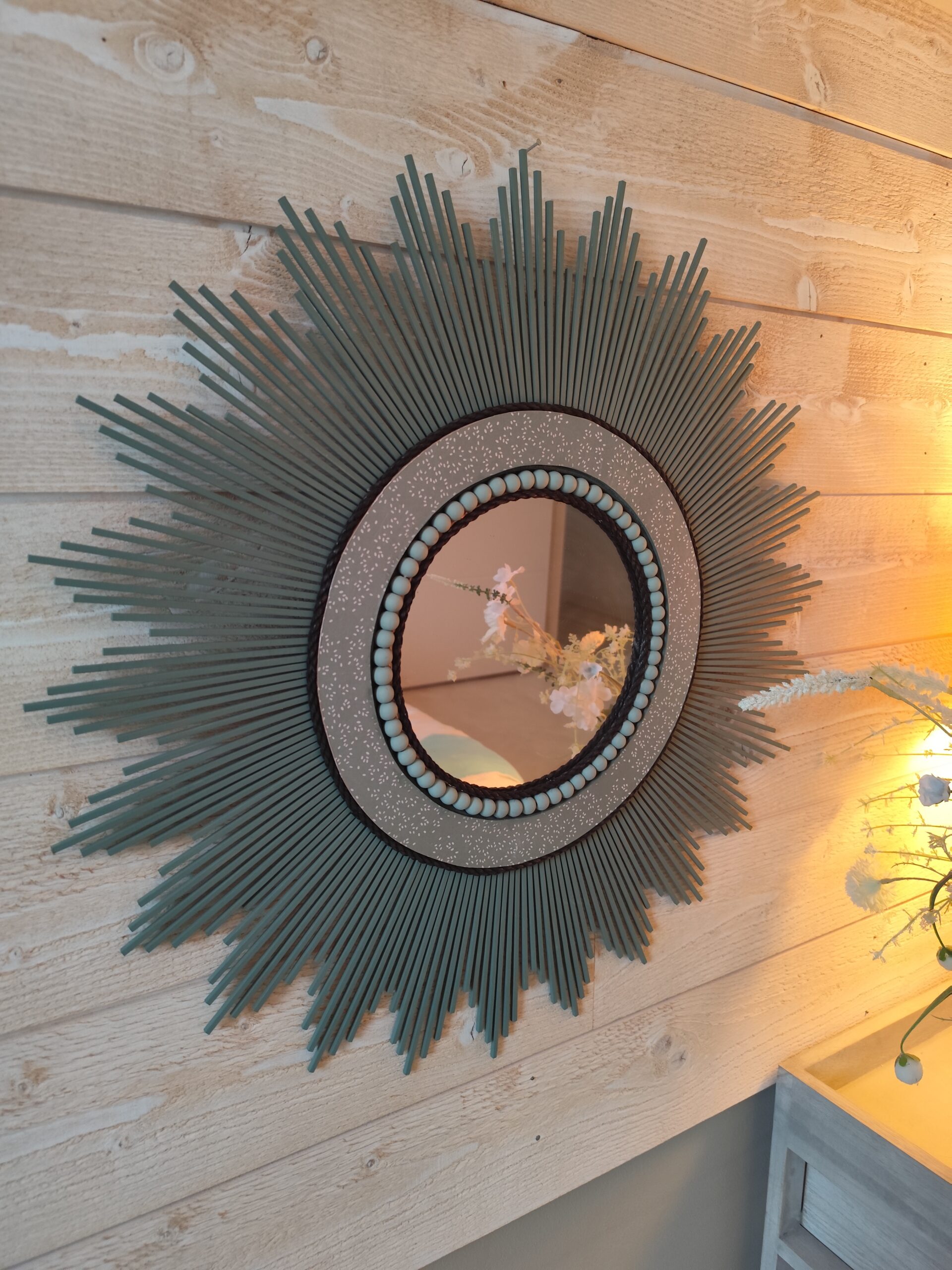 Décoration soleil.Miroir rond en bois teinté vert sauge, cerné d’éléments déco et de perles en bois.Ju0278