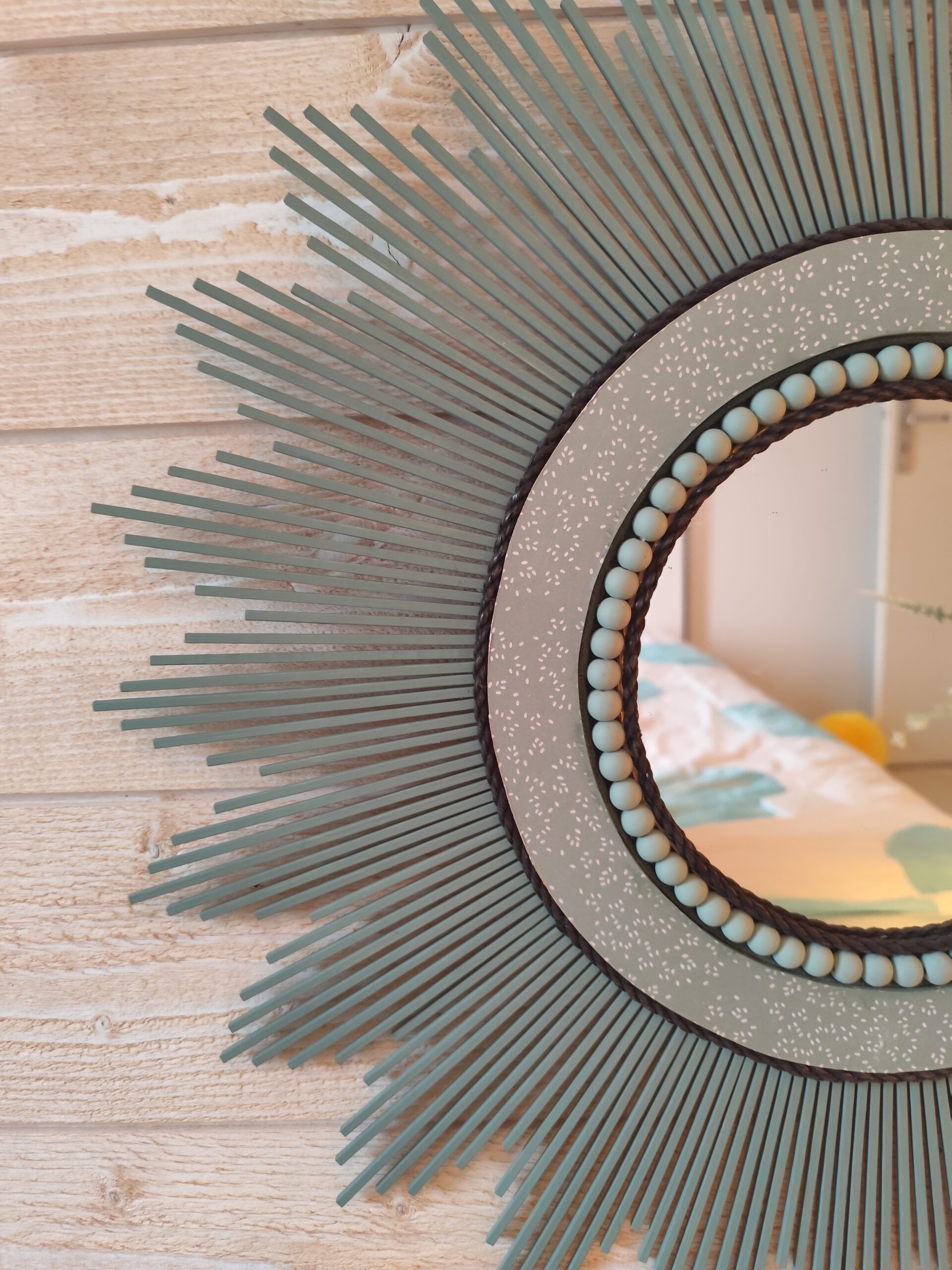 Décoration soleil.Miroir rond en bois teinté vert sauge, cerné d’éléments déco et de perles en bois.Ju0278