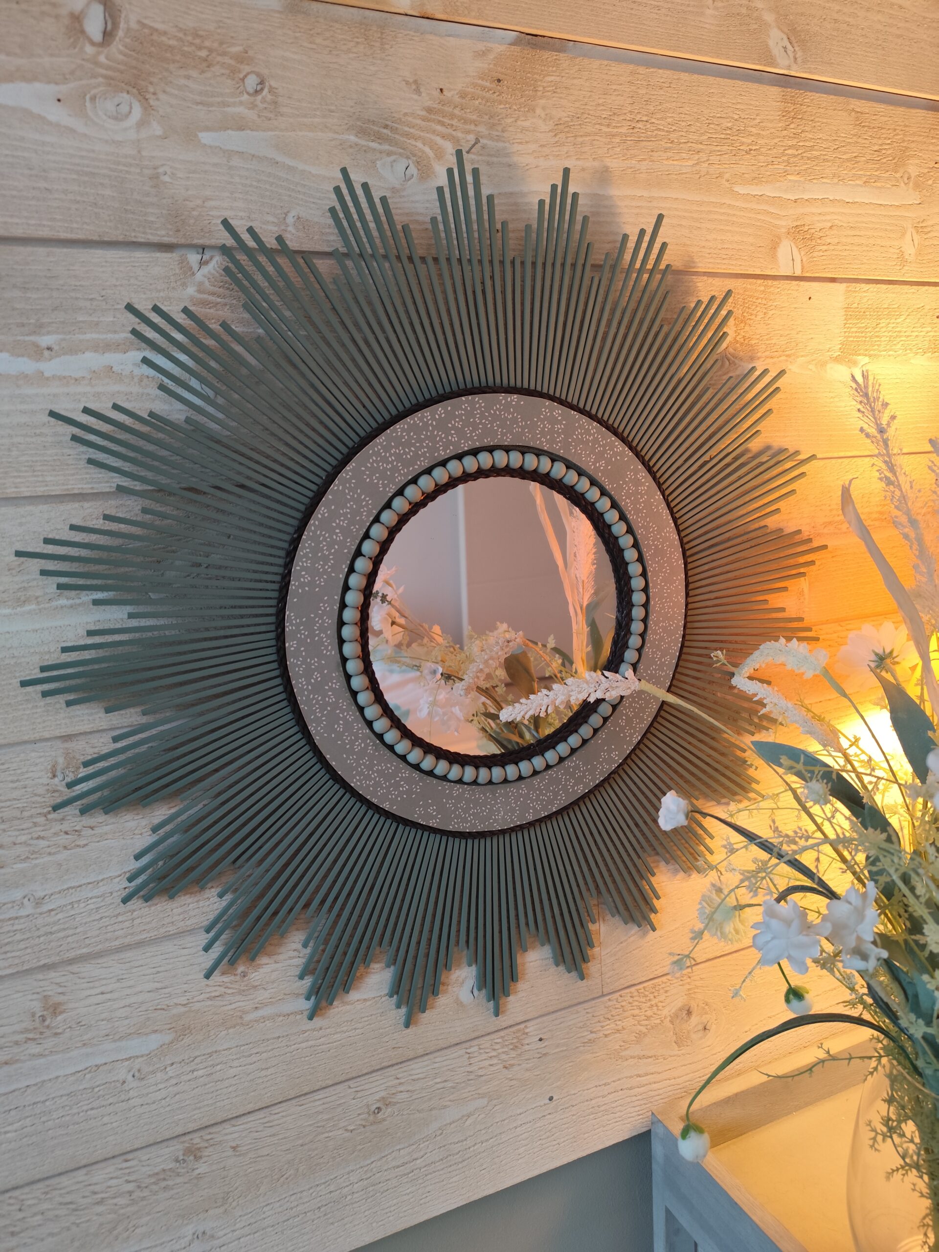 Décoration soleil.Miroir rond en bois teinté vert sauge, cerné d’éléments déco et de perles en bois.Ju0278