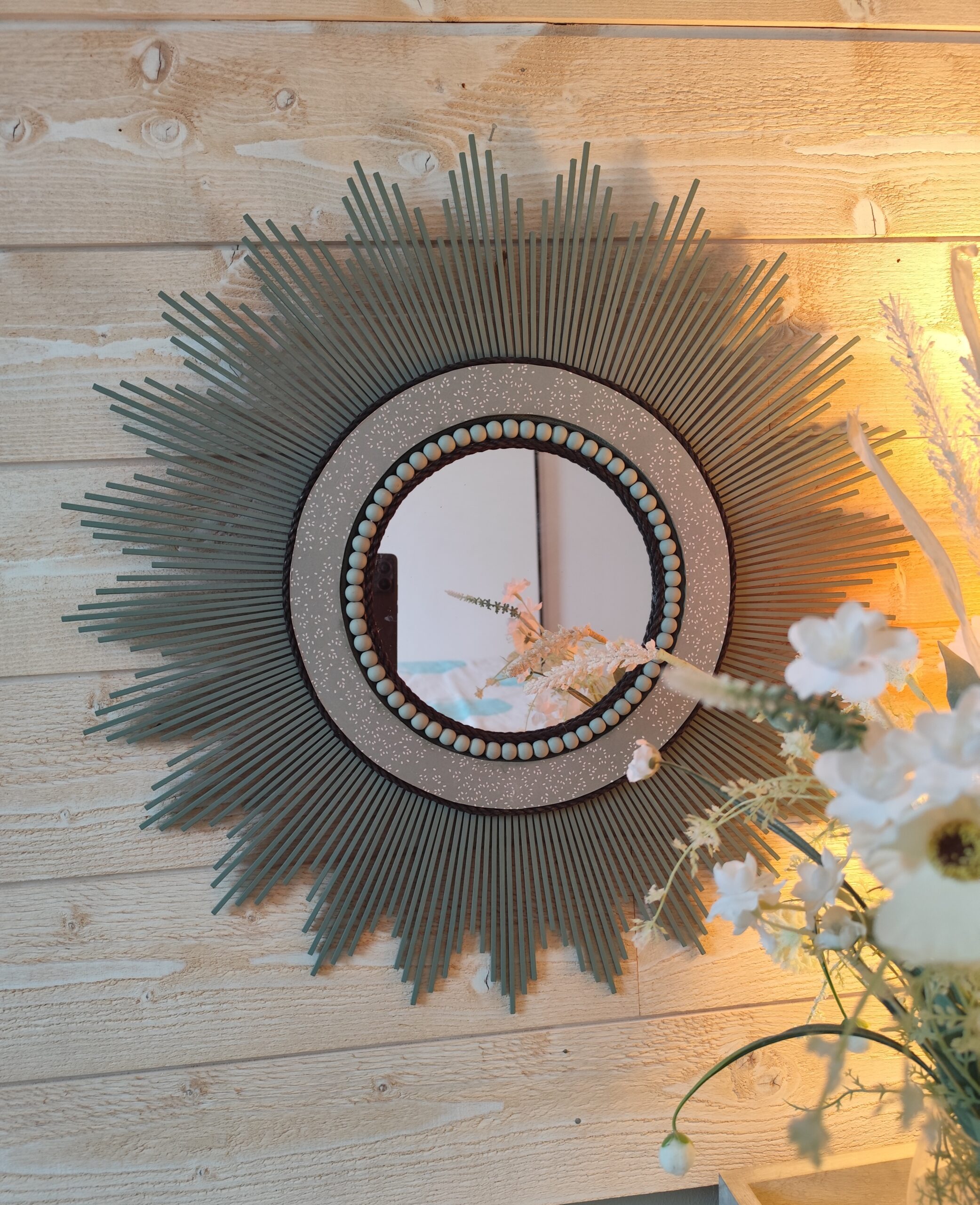 Décoration soleil.Miroir rond en bois teinté vert sauge, cerné d’éléments déco et de perles en bois.Ju0278