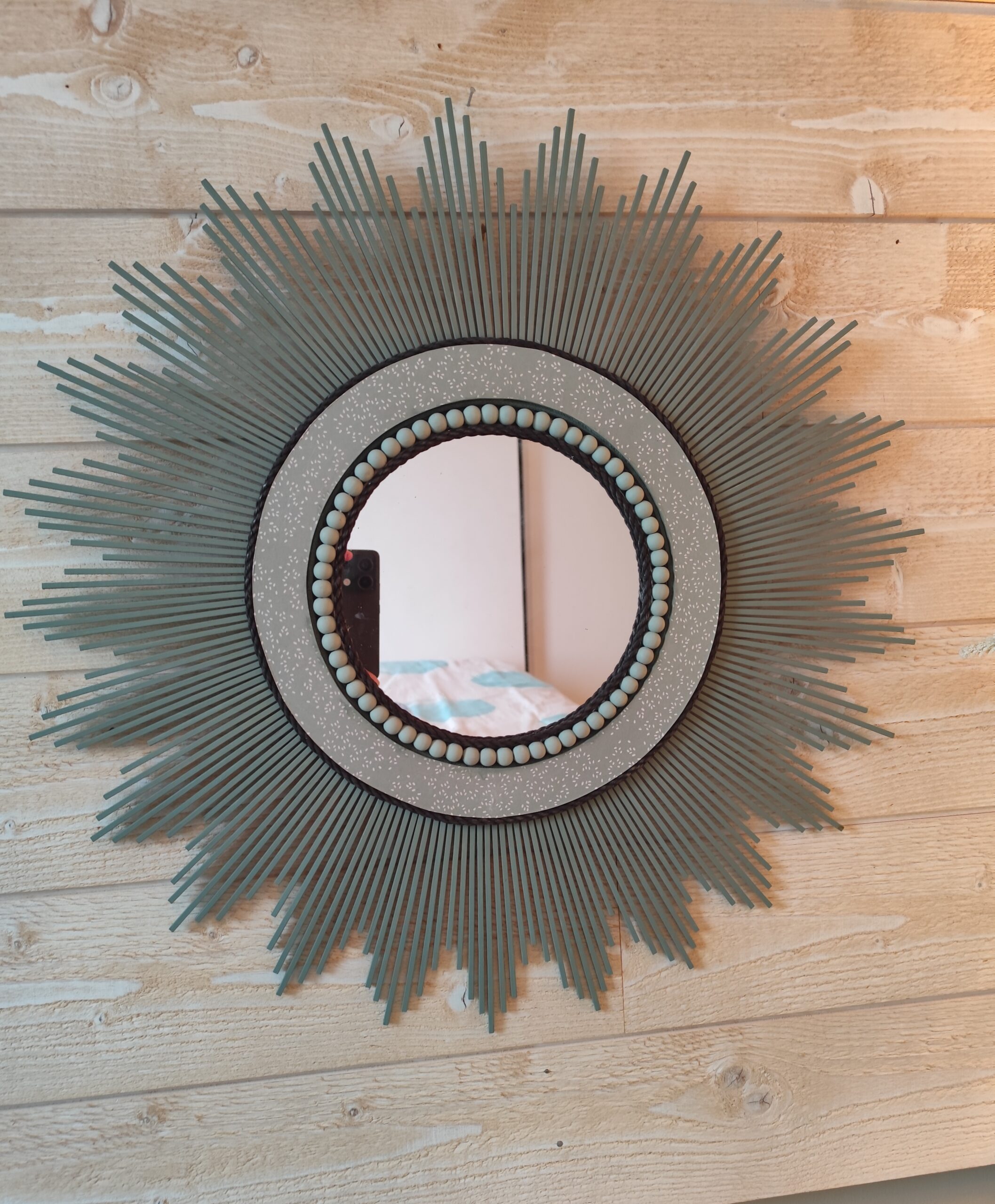 Décoration soleil.Miroir rond en bois teinté vert sauge, cerné d’éléments déco et de perles en bois.Ju0278